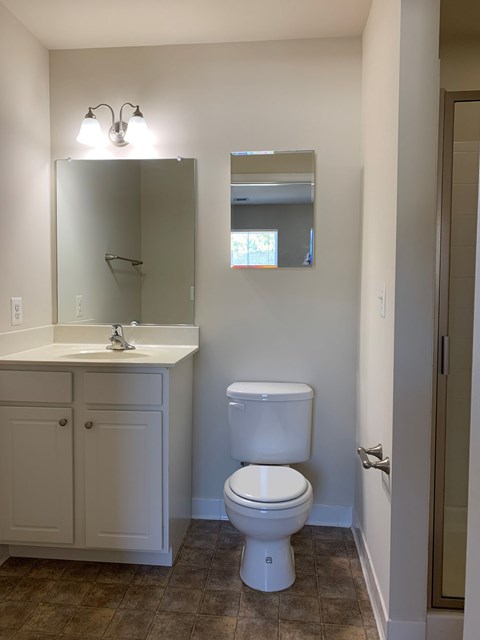 A white toilet sits in a bathroom next to a sink and medicine cabinet.