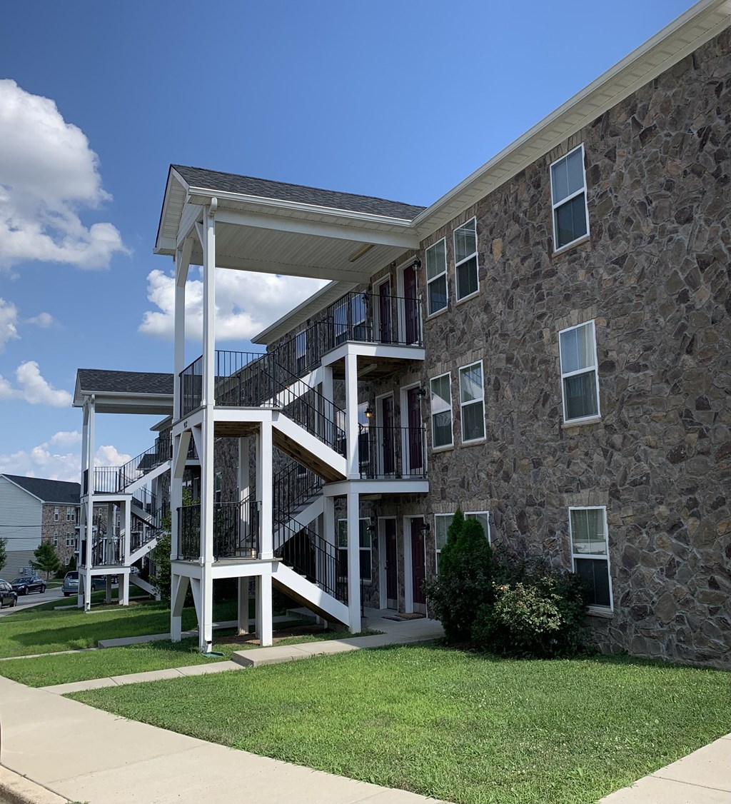 an exterior view of a building with stairs and a lawn