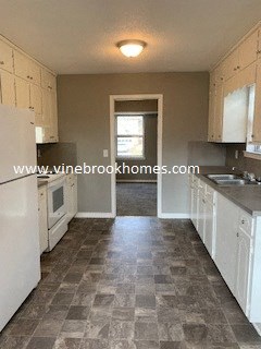 a kitchen with white cabinets and a sink and a window