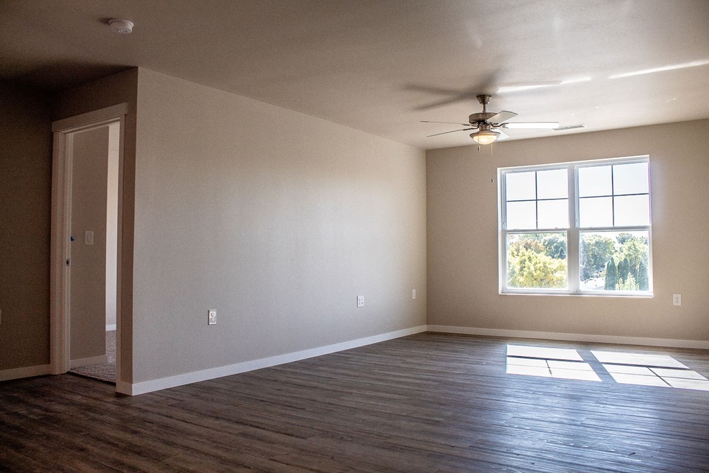 an empty living room with a ceiling fan and a window