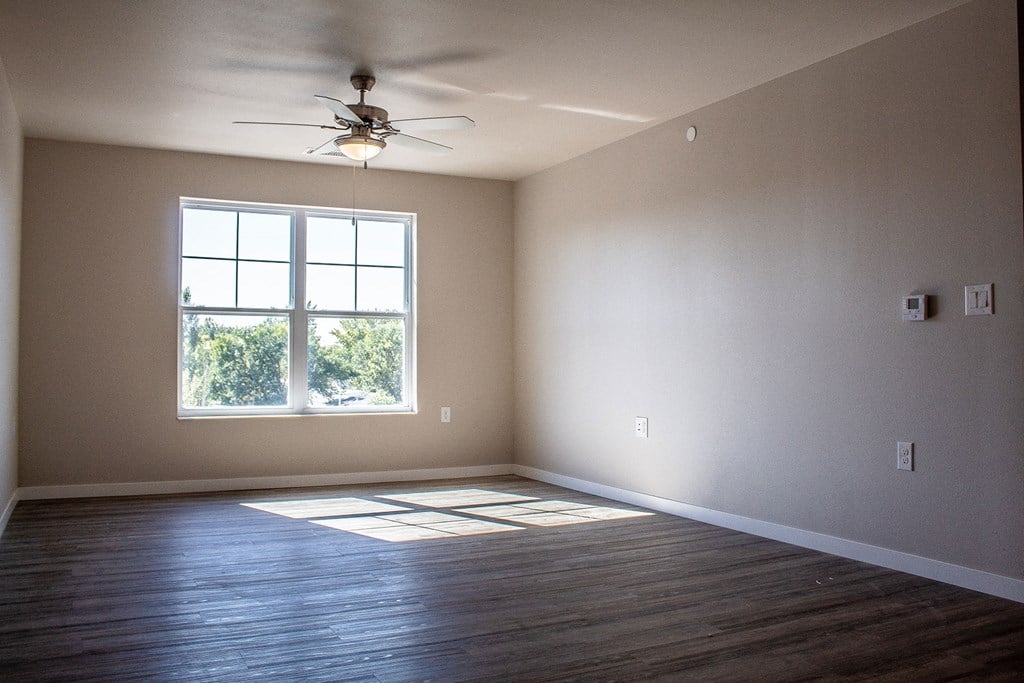an empty living room with a ceiling fan and a window