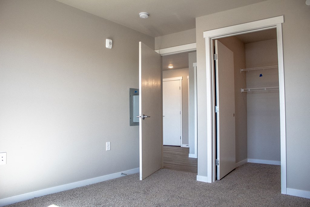 a bedroom with a closet and a hallway with a door open
