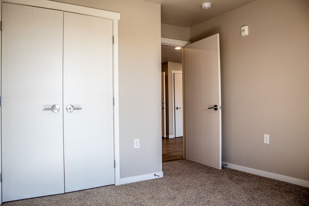 a bedroom with two closet doors and a door to a hallway