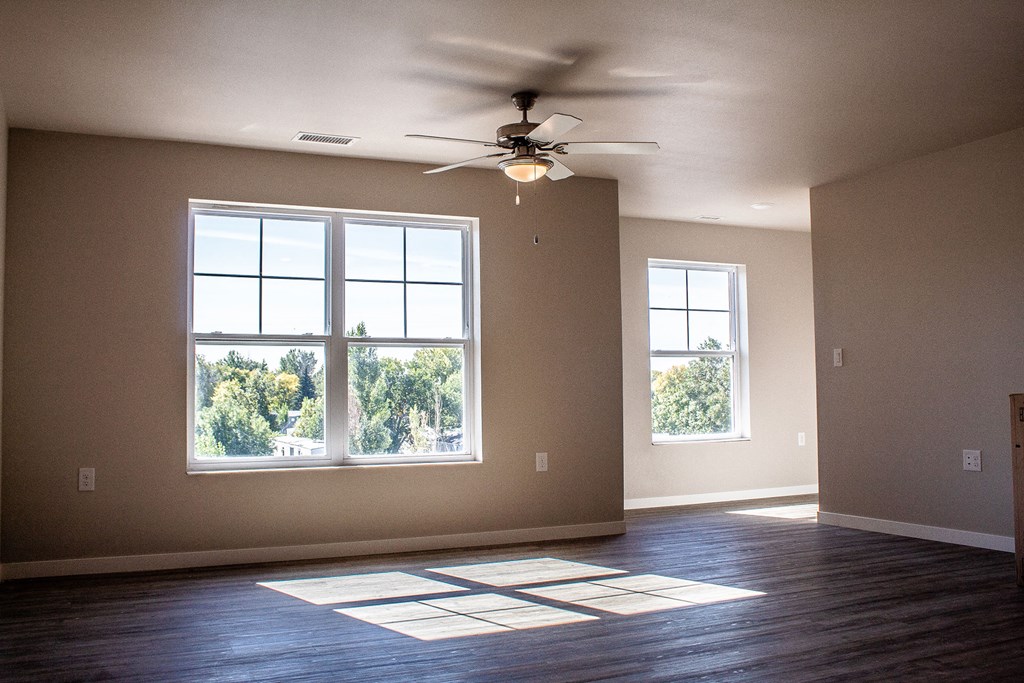 an empty living room with a ceiling fan and a window