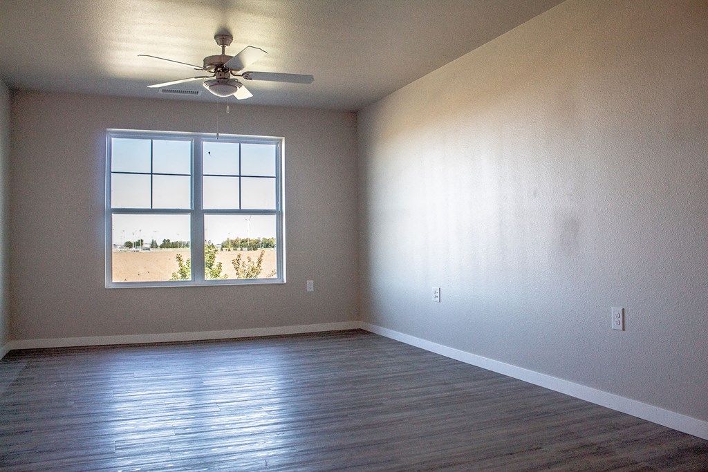 an empty living room with a ceiling fan and a window