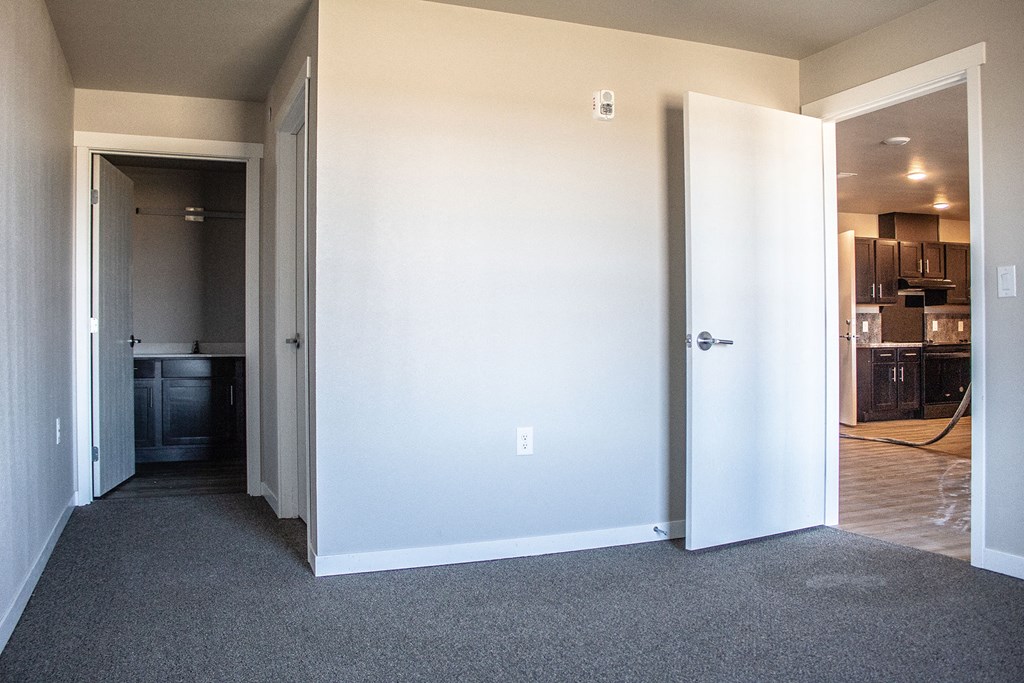 a room with a door open and a hallway to a kitchen