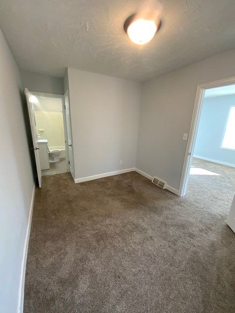 A room with a carpeted floor and a doorway leading to another room.