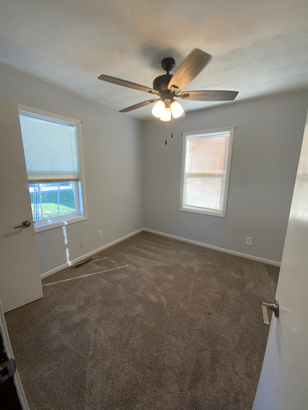 A room with a ceiling fan and carpeted floor.
