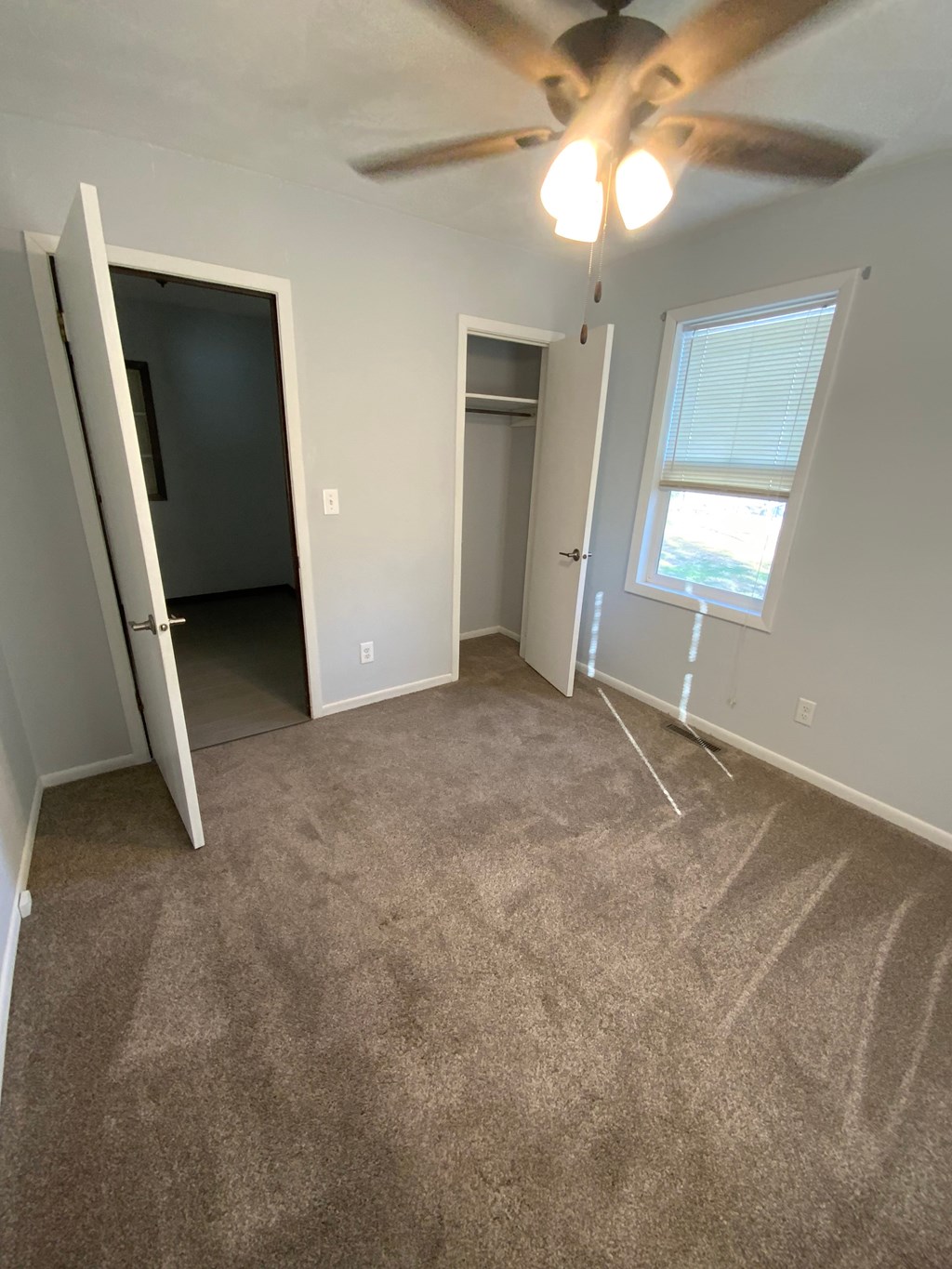 A room with a ceiling fan and carpeted floor.