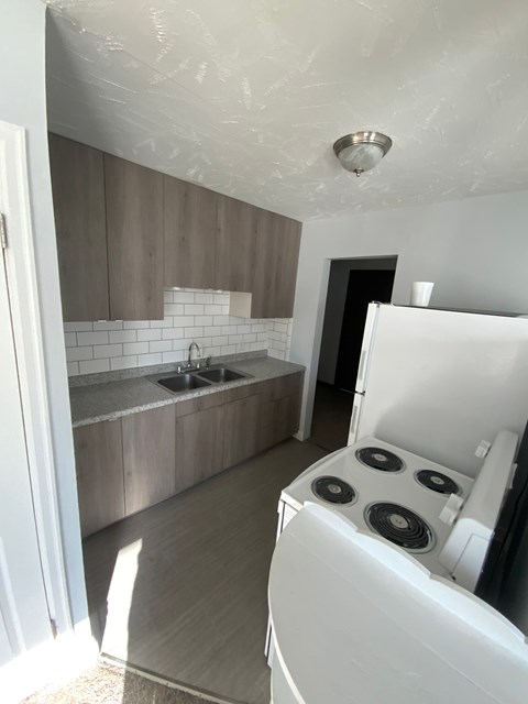 A white oven in a kitchen with wooden cabinets and a white fridge.