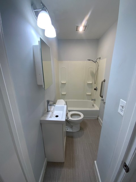 A small white bathroom with a toilet, sink, and shower.