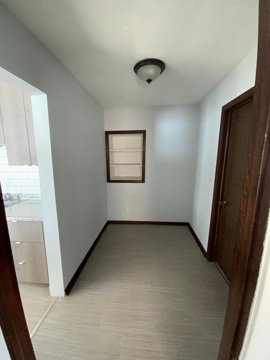 A room with a brown door and a window with blinds.
