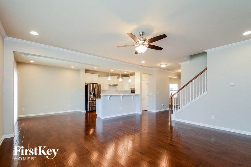 an empty living room with a ceiling fan and a kitchen