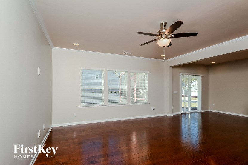 an empty living room with wood floors and a ceiling fan