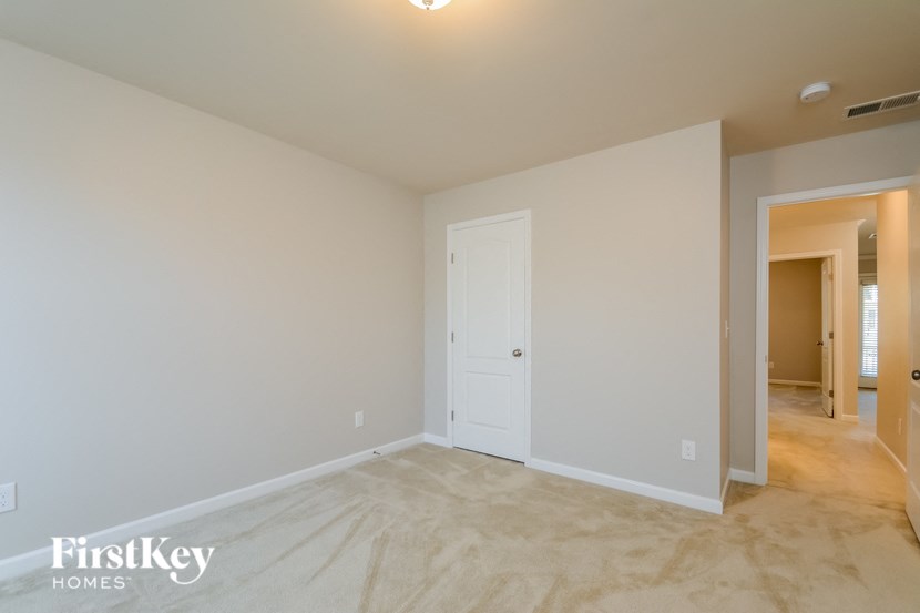 an empty living room with a white door and a hallway