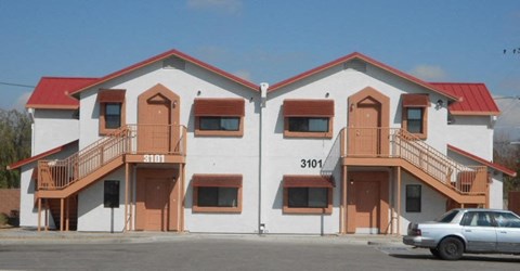 A white building with red roof and a car in front.