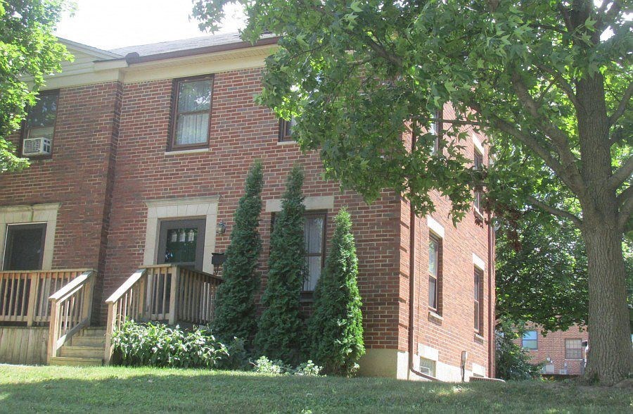 a brick house with a porch and a tree