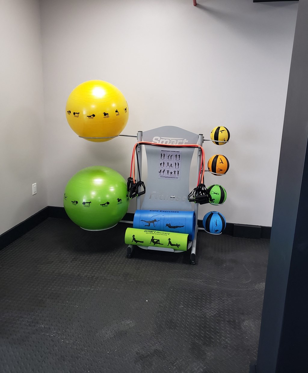 a workout room with green and yellow balls and an exercise machine