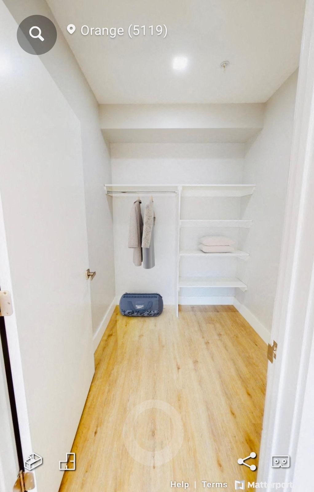 a small closet with white shelves and a wood floor