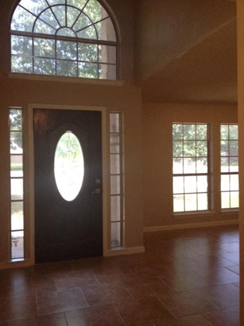 an empty living room with a black door and windows