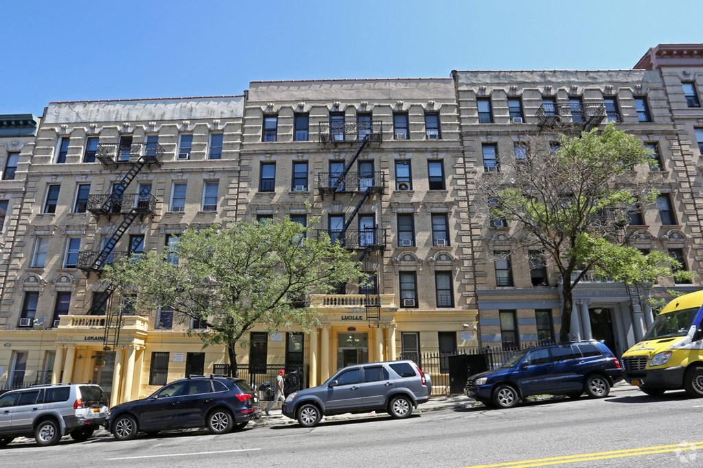 A yellow building with a black car in front of it.