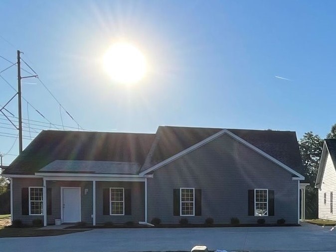 A house with a grey roof and white door is bathed in sunlight.