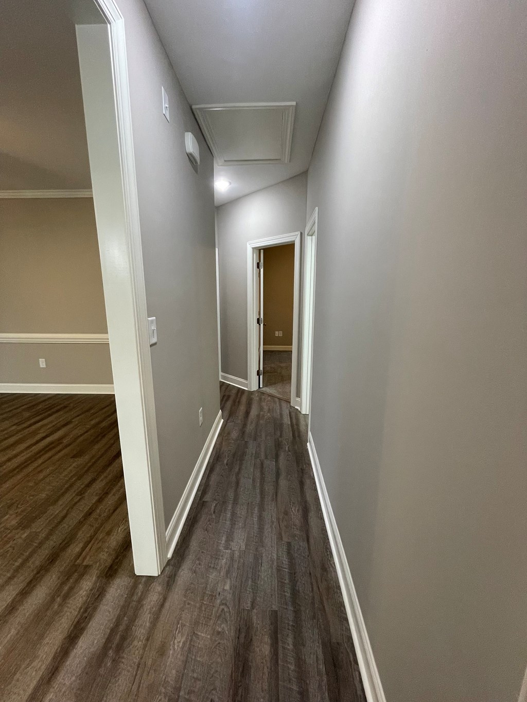A long hallway with wood flooring and white walls.