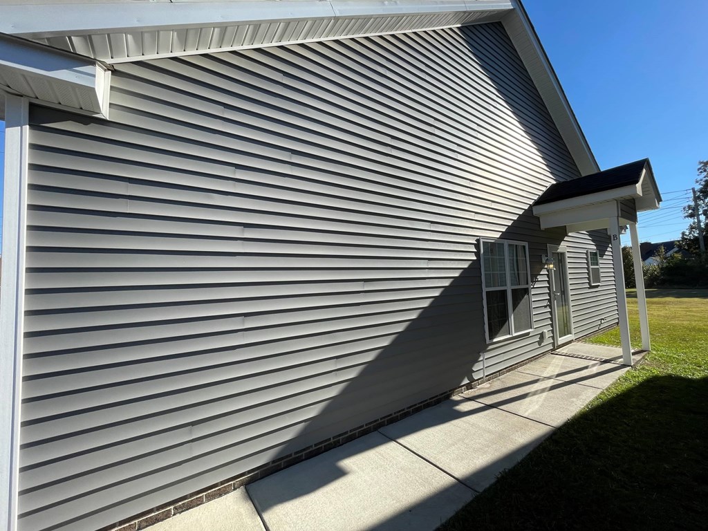 A house with a grey siding and a white roof.