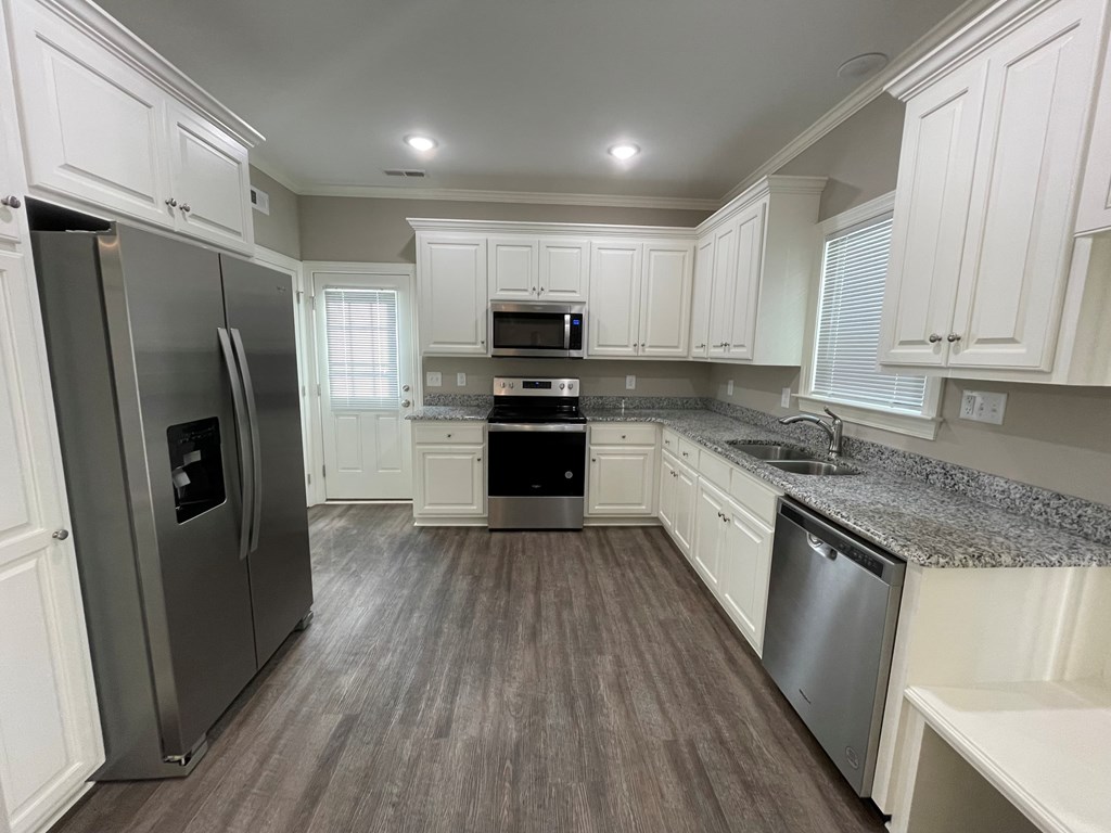 A kitchen with white cabinets and a grey refrigerator.