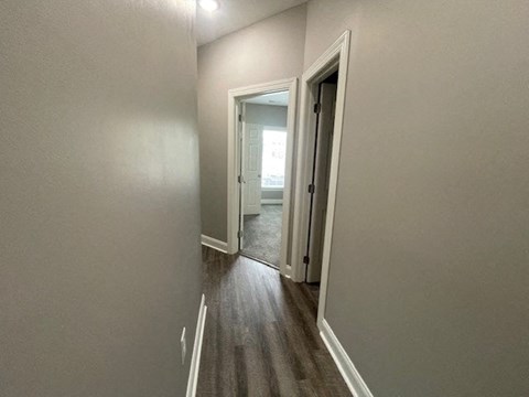 a hallway with a doorway to a bedroom and a door to a bathroom
