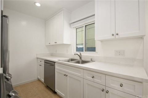 A kitchen with white cabinets and a marble countertop.