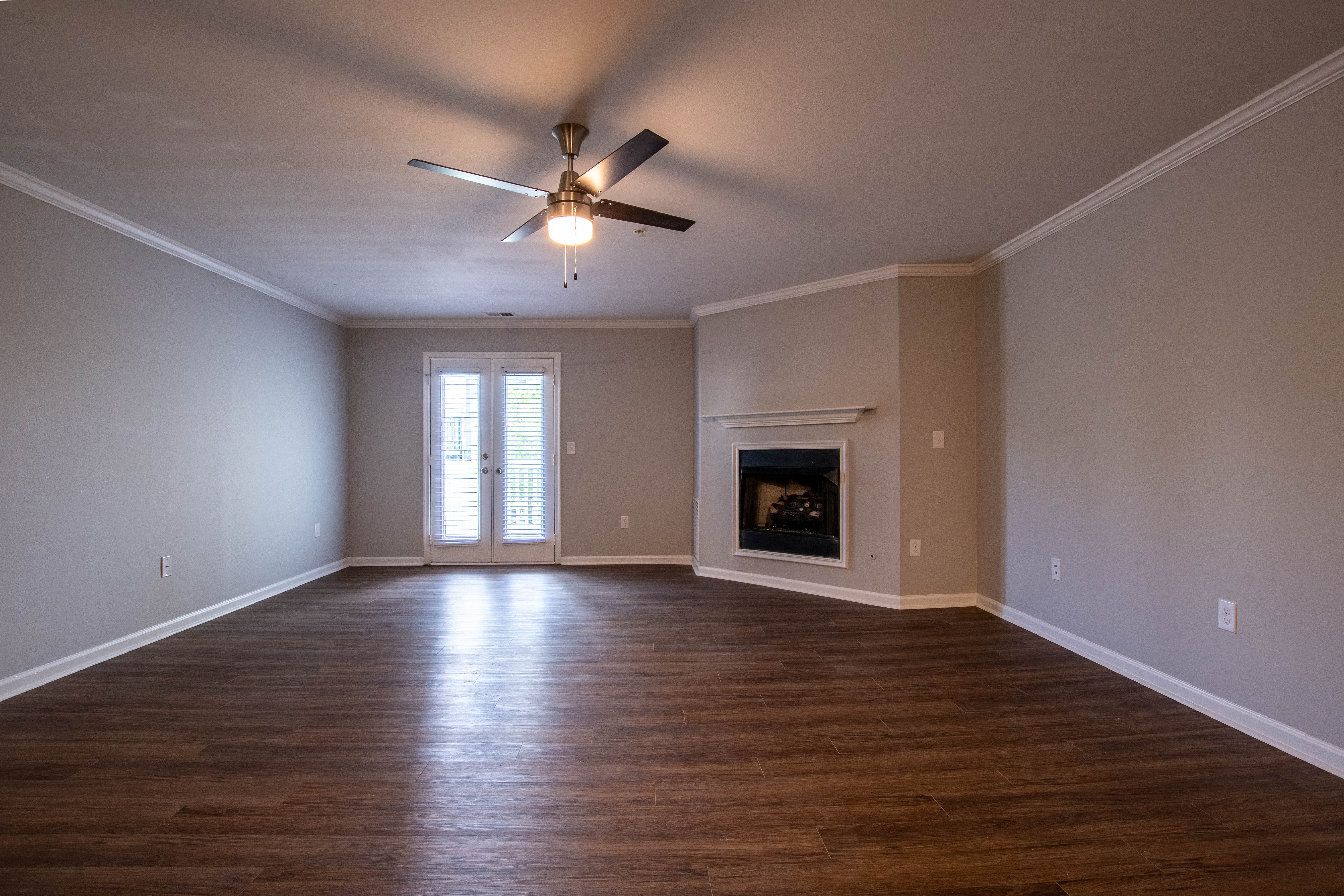 an empty living room with a ceiling fan and a fireplace