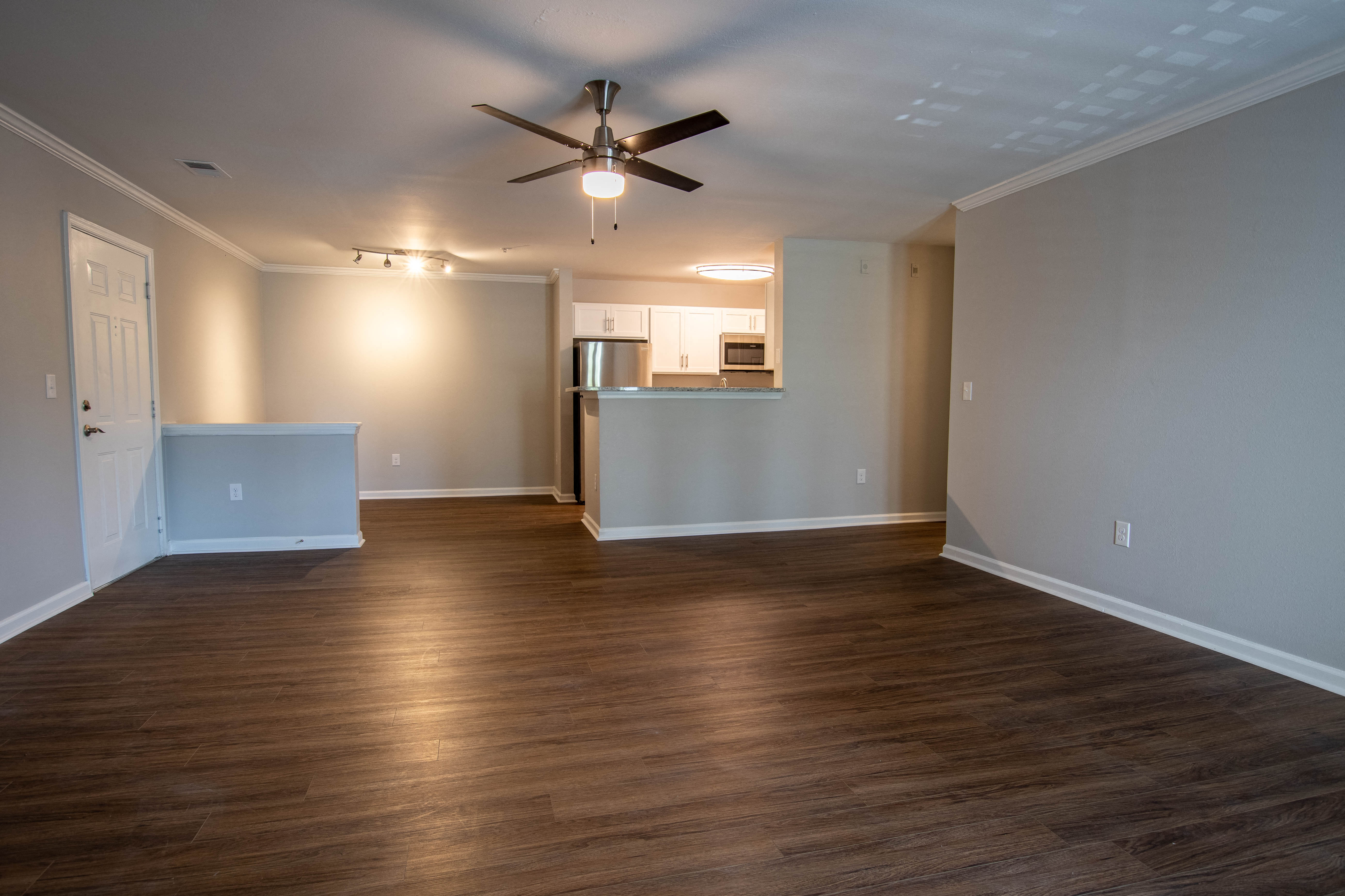 an empty living room with wood floors and a ceiling fan