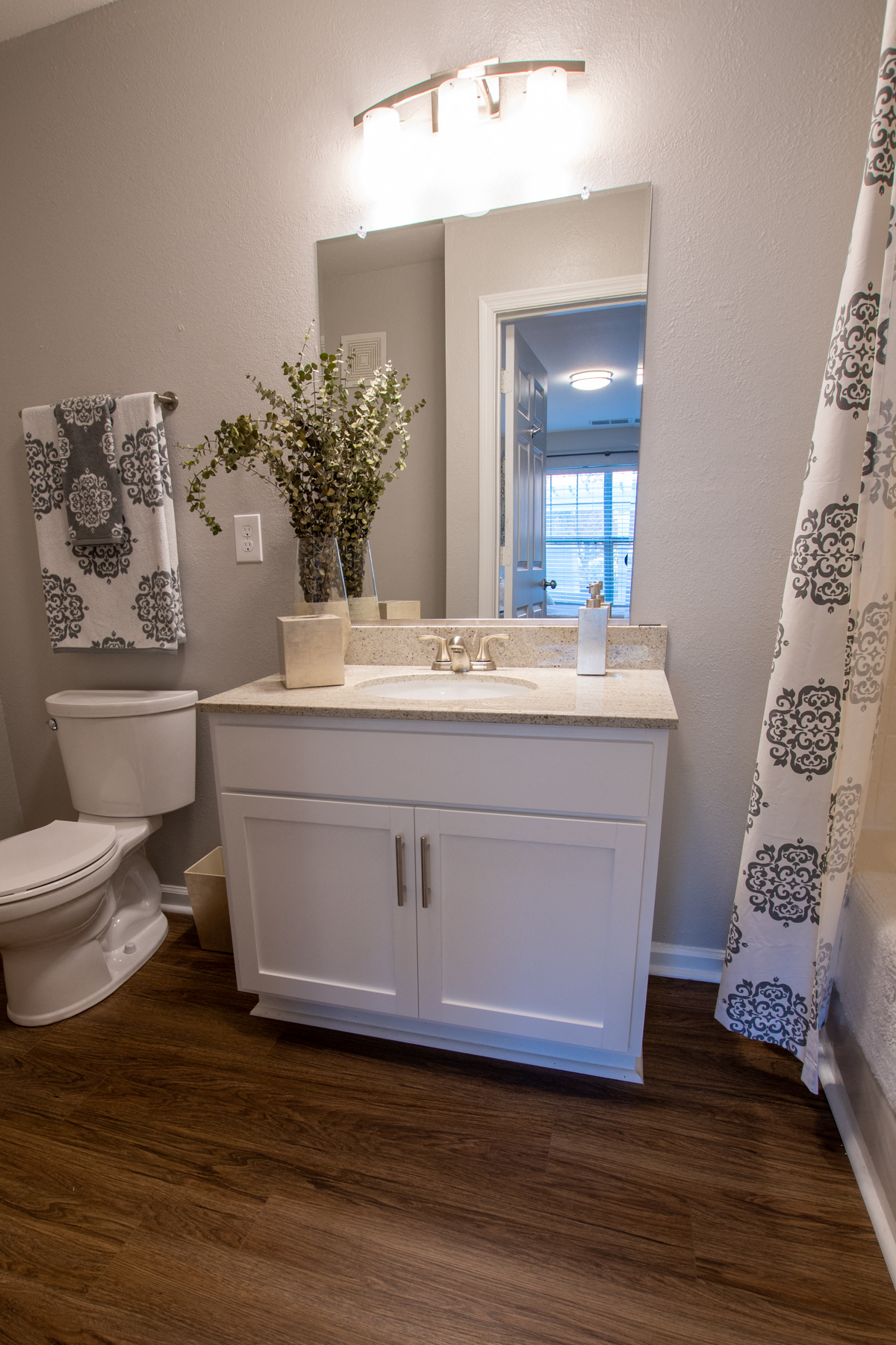 a bathroom with a toilet sink and mirror and a shower curtain