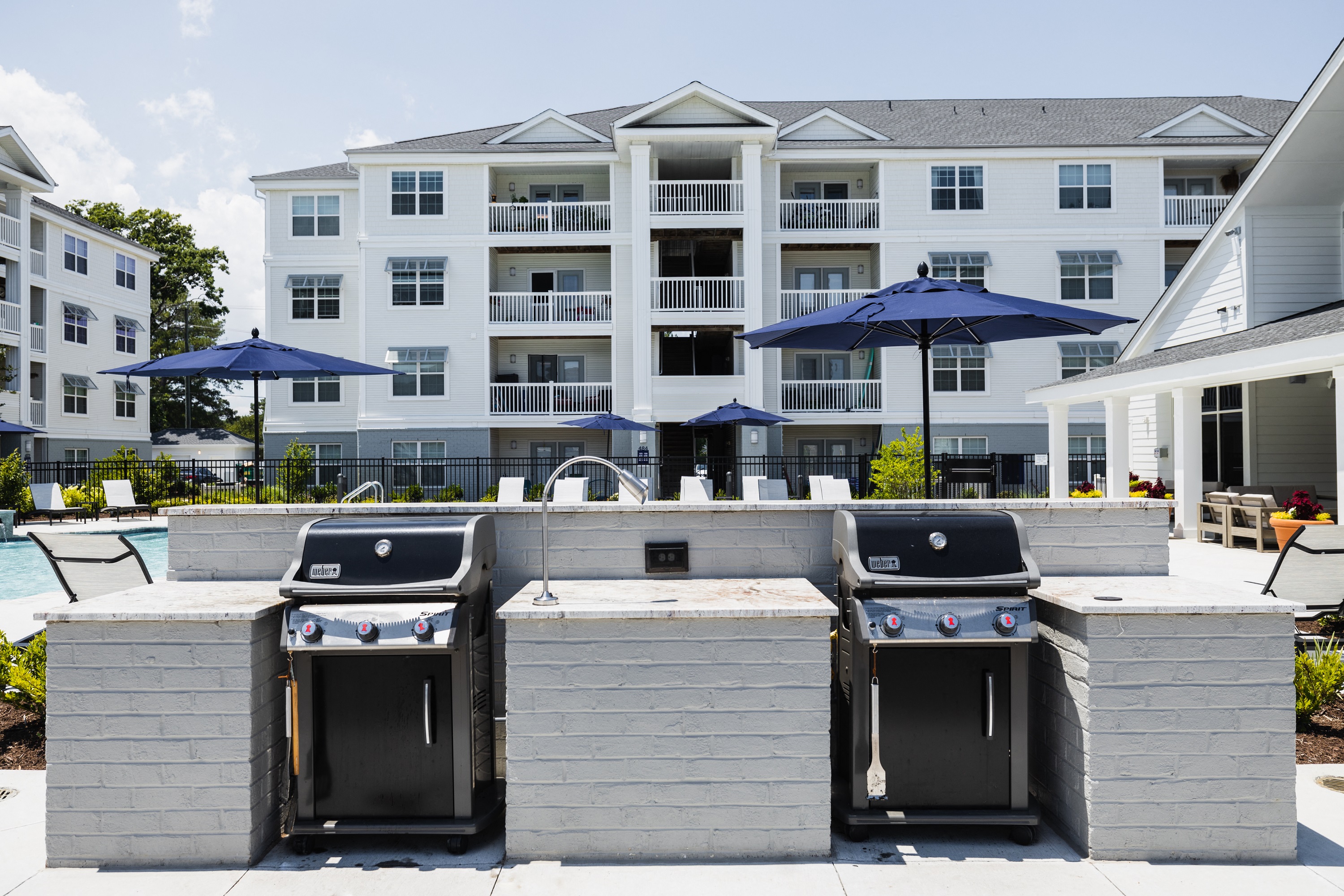 two outdoor grills with umbrellas in front of an apartment building