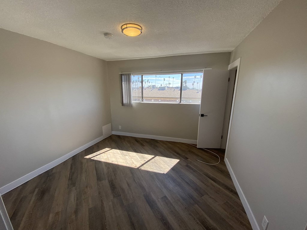 an empty living room with wood floors and a window