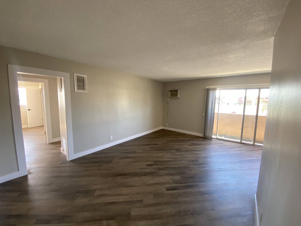 an empty living room with a hard wood floor and white walls