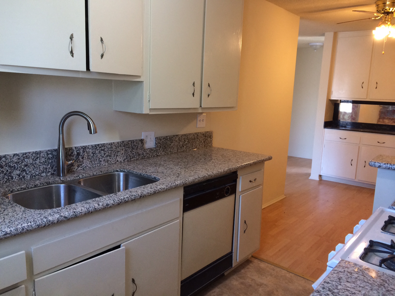 a kitchen with white cabinets and granite counter tops and a sink