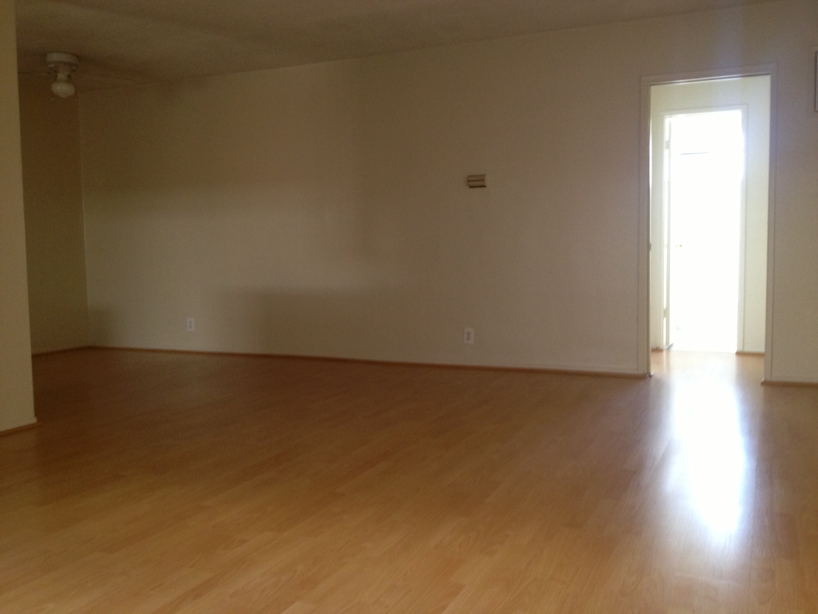 an empty living room with wooden floors and white walls