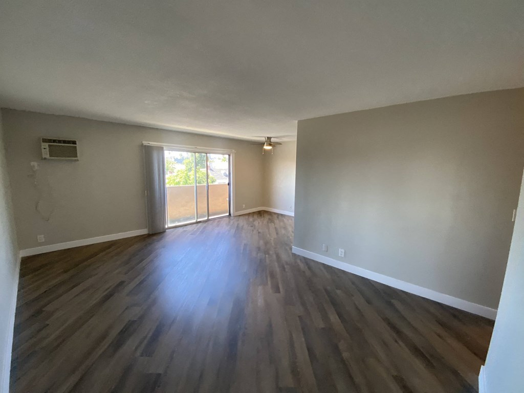 an empty living room with wooden floors and a window