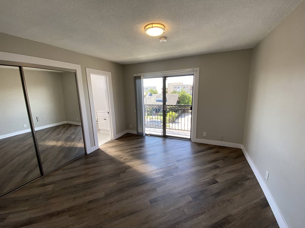 an empty living room with hard wood floors and a sliding glass door