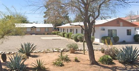 a house with a gravel driveway and a tree in front of it