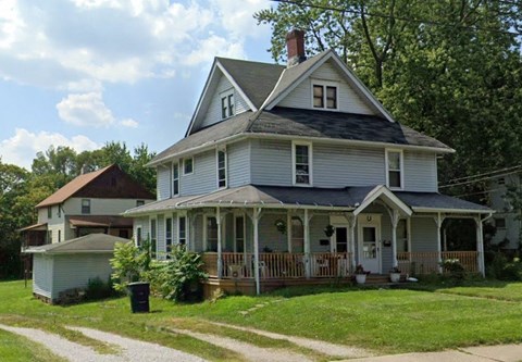 A two-story house with a porch and a chimney.