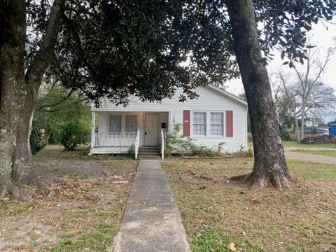 a small white house with a sidewalk in front of it