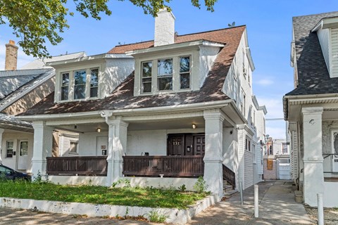 A white house with a brown roof and a balcony.