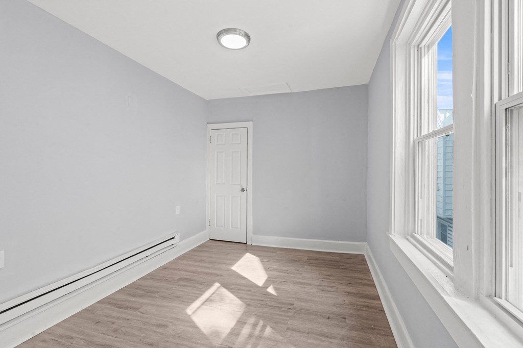 an empty room with two large windows and a white door