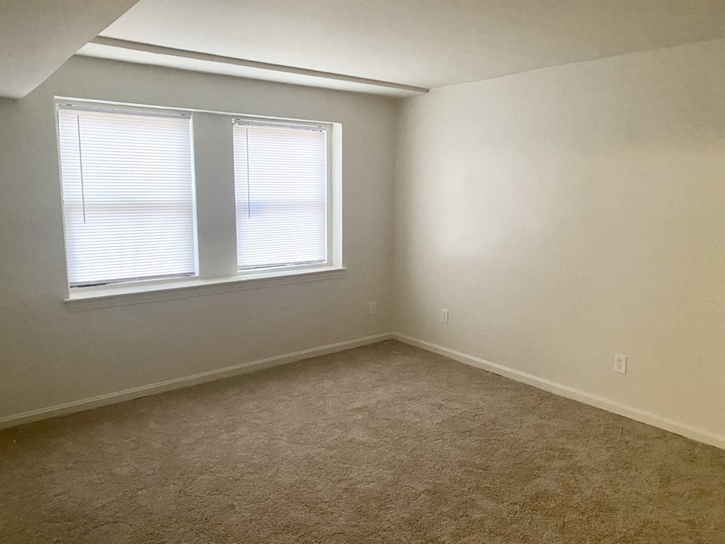 an empty room with a window and a carpet