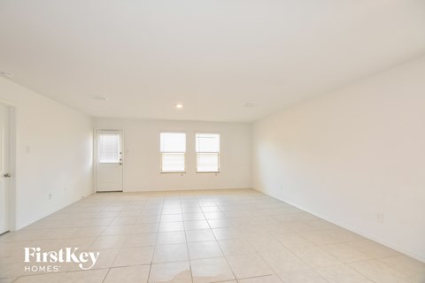 A spacious empty room with a tiled floor and two windows.