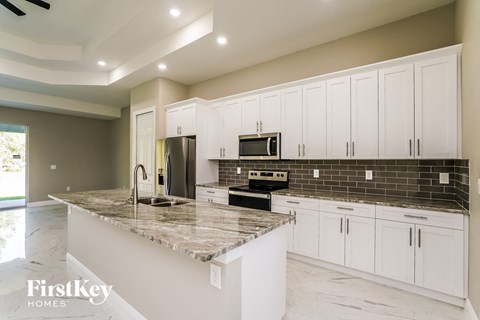 A kitchen with white cabinets and a marble countertop.