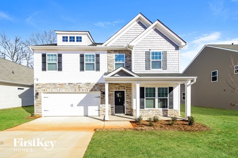 A two-story house with a garage on the first floor and a balcony on the second floor.